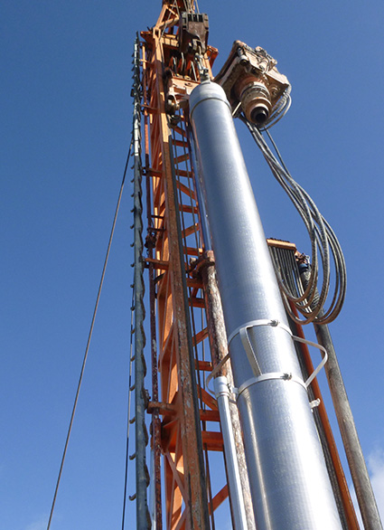 Nahaufnahme eines Bohrturms mit Fokus auf die Stahlseile und den Bohrmechanismus vor einem klaren blauen Himmel