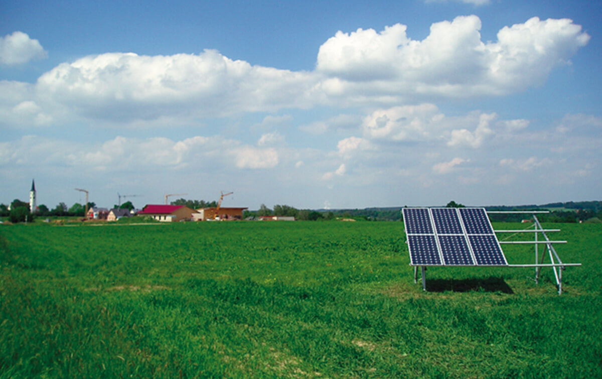 Solarpaneel auf Wiese mit Dorf im Hintergrund